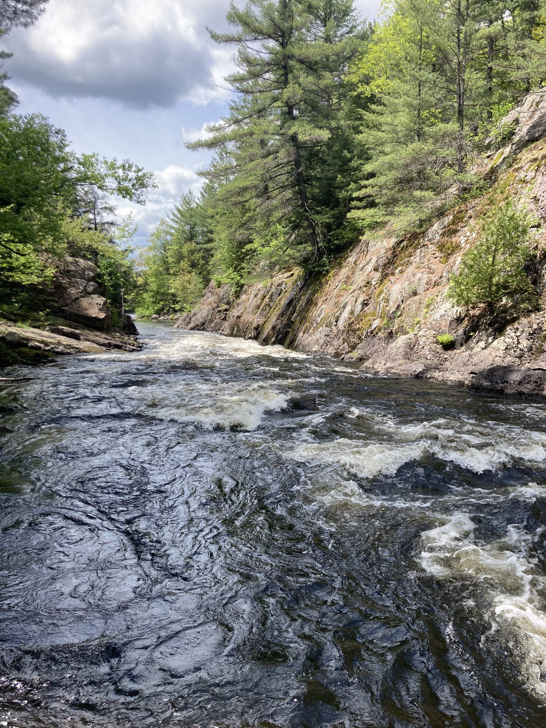 A photo of a moving river with a rock cliff on one side.